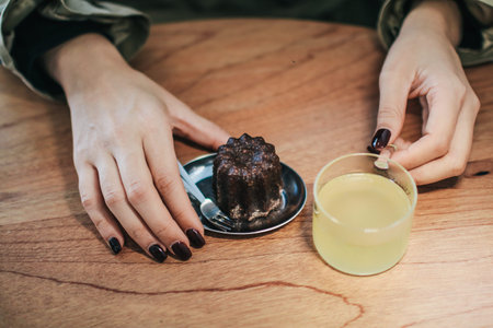 Woman eat CanelÃ© de Bordeaux with lemonade, traditional French confectionery. French sweet...