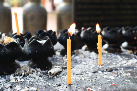 Burning yellow candle in temple creates a spiritual and peaceful atmosphere. Buddhist ceremony and Paying respect to Buddha.の写真素材