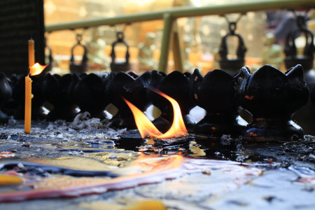 Candles lit on oil in temple creates spiritual and peaceful atmosphere. Buddhist ceremony and Paying respect to Buddha.の写真素材