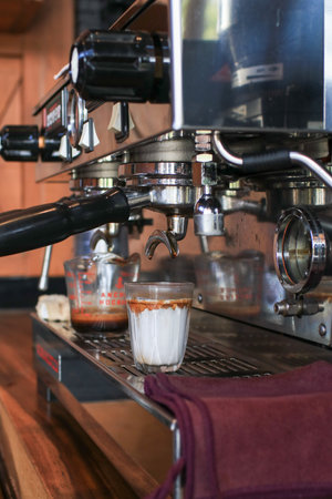 Coffee machine making espresso shot on fresh milk create gradient layer called dirty coffee.の写真素材