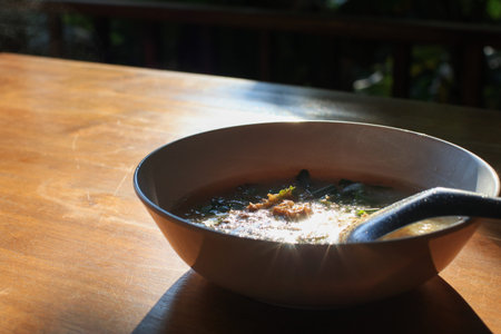 Boiled rice in white bowl on wooden table with morning sunlight. Asian breakfast style. Pork Porridge.の写真素材