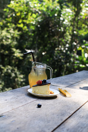 Basque cheesecake with berry and refreshing drink. Delicious homemade pastry on wooden table.の写真素材