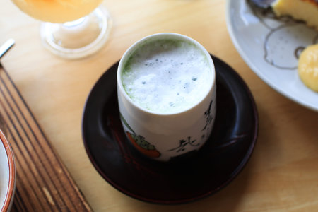 Hot matcha in tradition ceramic clay cup. Warm natural tones, Japanese tea style, and cozy cafe.の写真素材