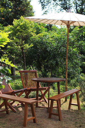 Empty wooden chair and table with umbrella in garden. Summer relax outdoors.の写真素材