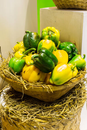 Wicker basket full of sweet green, yellow and red bell peppers .の写真素材