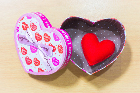 Valentines Day gift box and rose with heart on wooden plates. Sweet holiday backgroundの写真素材