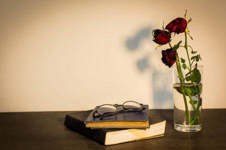 Roses in glass and glasses on  old books, vintage style.の写真素材