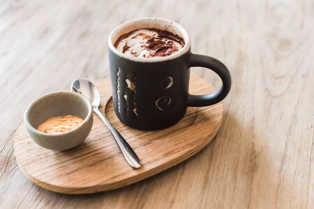 brown cup of hot chocolate with creamy milk and cookie on wood tableの写真素材