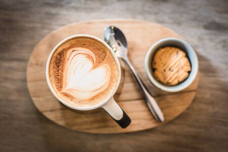 Hot Latte Coffee heart art and cookie on the wooden tableの写真素材
