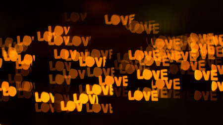 Abstract romantic background of defocused bokeh with word love, on black background.の写真素材