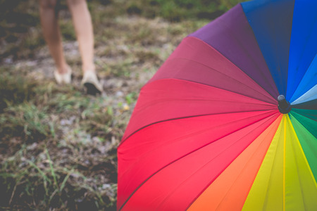 Farewell rainbow umbrella in grass field vintage and retro tone, soft focusの写真素材