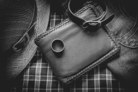 still life photography : Brown leather wallet, Leather wristbands, silver ring and adventure hat on jeans background,  men casual concept, vintage and retro style.の写真素材