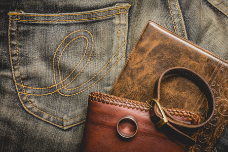 still life photography : Brown leather wallet, Leather wristbands, silver ring and adventure hat on jeans background,  men casual concept, vintage and retro style.の写真素材