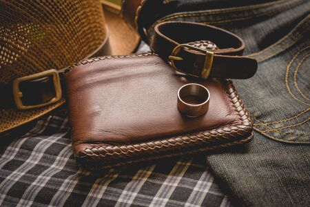 still life photography : Brown leather wallet, Leather wristbands, silver ring and adventure hat on jeans background,  men casual concept, vintage and retro style.の写真素材