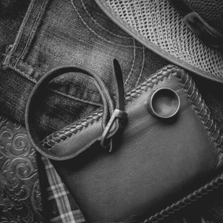still life photography : Brown leather wallet, Leather wristbands, silver ring and adventure hat on jeans background,  men casual concept, vintage and retro style.の写真素材
