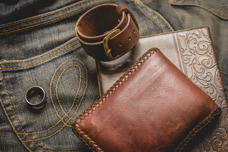 still life photography : Brown leather wallet, Leather wristbands, silver ring and adventure hat on jeans background,  men casual concept, vintage and retro style.の写真素材