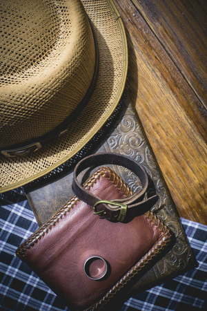 still life photography : Brown leather wallet, Leather wristbands, silver ring and adventure hat on jeans background, men casual concept, vintage and retro styleの写真素材