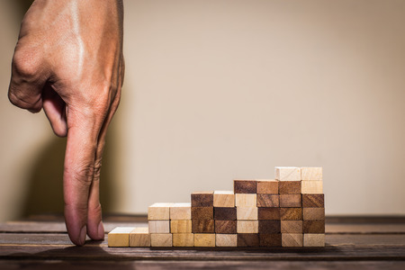 Hand liken business person stepping up a toy staircase.の写真素材