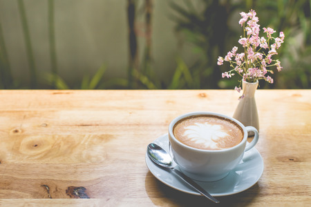 latte art coffee with flowers on wooden table, vintage and retro style.の写真素材