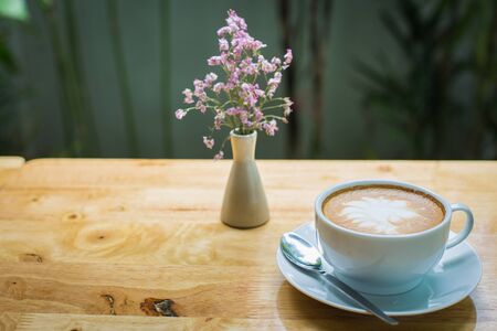 latte art coffee with flowers on wooden table, vintage and retro style.の写真素材