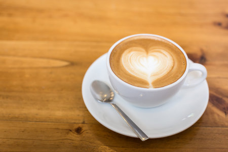 Hot art Latte Coffee in a cup on wooden tableの写真素材
