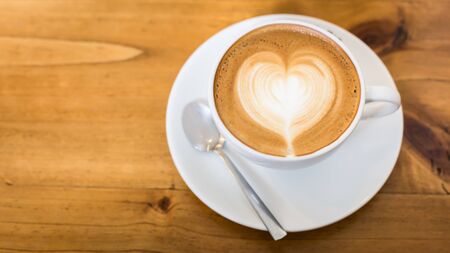 Hot art Latte Coffee in a cup on wooden tableの写真素材