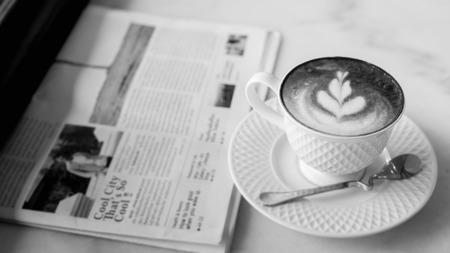 hot latte art coffee with newspaper on wooden table, vintage and retro styleの写真素材