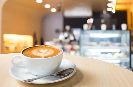 Hot art Latte Coffee in a cup on wooden table and Coffee shop blur background with bokeh imageの写真素材