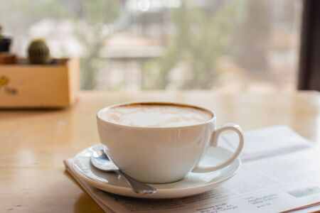 Hot latte art coffee cup with newspaper on wooden table, vintage and retro styleの写真素材