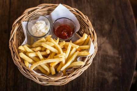 Traditional French fries with ketchup on wooden table.の写真素材