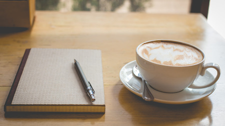 Hot latte art coffee cup on wooden table, vintage and retro styleの写真素材