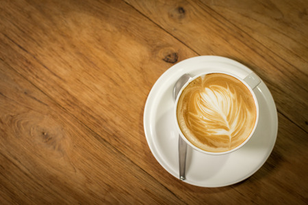 Hot art Latte Coffee in a cup on wooden table and Coffee shop blur background with bokeh image.の写真素材