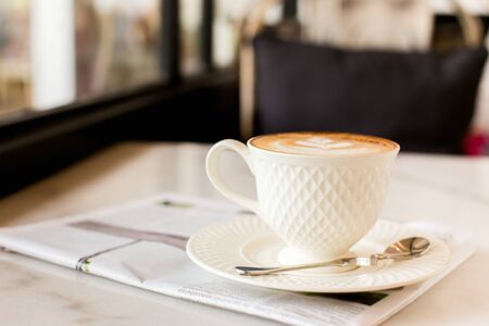 hot latte art coffee with newspaper on wooden table, vintage and retro styleの写真素材