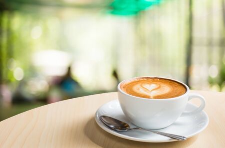Hot art Latte Coffee in a cup on wooden table and Coffee shop blur background with bokeh image.の写真素材