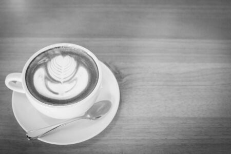 Hot art Latte Coffee in a cup on wooden table and Coffee shop blur background with bokeh image black and white tone.の写真素材