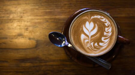 Hot art Latte Coffee in a cup on wooden table and Coffee shop blur background with bokeh image.の写真素材