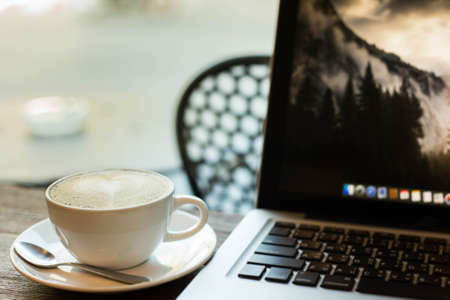 Hot art Latte Coffee in a cup on wooden table and Coffee shop blur background with bokeh image.の写真素材