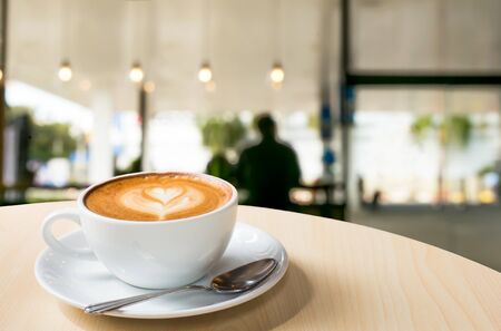 Hot art Latte Coffee in a cup on wooden table and Coffee shop blur background with bokeh imageの写真素材