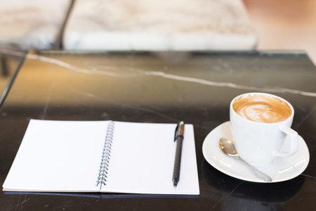 Hot latte art coffee cup on wooden table and note book