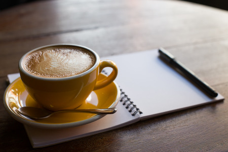 Hot latte art coffee cup on wooden table and note bookの写真素材