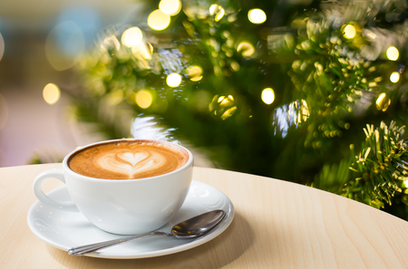 Photo of beautiful Christmas light festive, white coffee cup on the wooden table on bokeh background