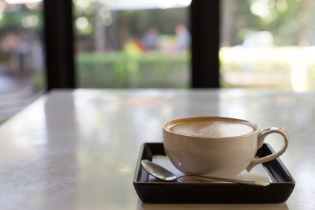 Hot art Latte Coffee in a cup and laptop on wooden tableの写真素材