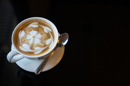 Hot art Latte Coffee in a cup and laptop on table.の写真素材