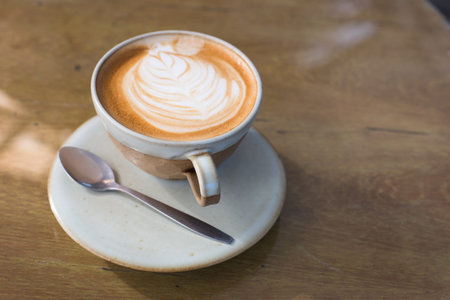 Hot art Latte Coffee in a cup and laptop on wooden table.
