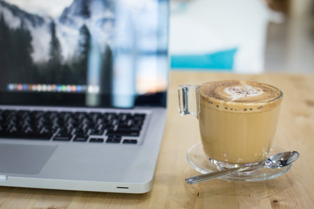 Hot art Latte Coffee in a cup on wooden table and Coffee shop blur background with bokeh image