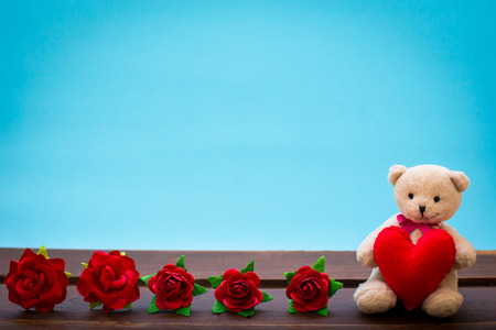 Teddy bear with pink heart decoration on wooden table over wall blue background, Valentine day concept.の写真素材