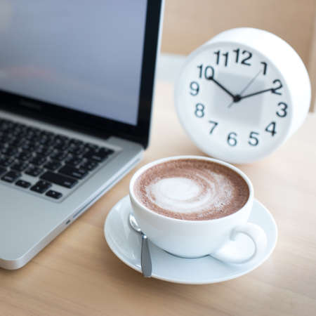 A cup of coffee in a white cup and computer labtop on mable table.の写真素材