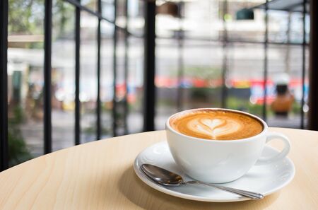 Hot art Latte Coffee in a cup on wooden table and Coffee shop blur background with bokeh image.の写真素材