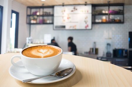 Hot art Latte Coffee in a cup on wooden table and Coffee shop blur background with bokeh image.の写真素材