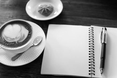 Coffee cup and notebook on table backgroundの写真素材